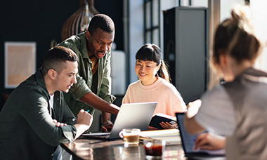 group of people working together and looking at laptop